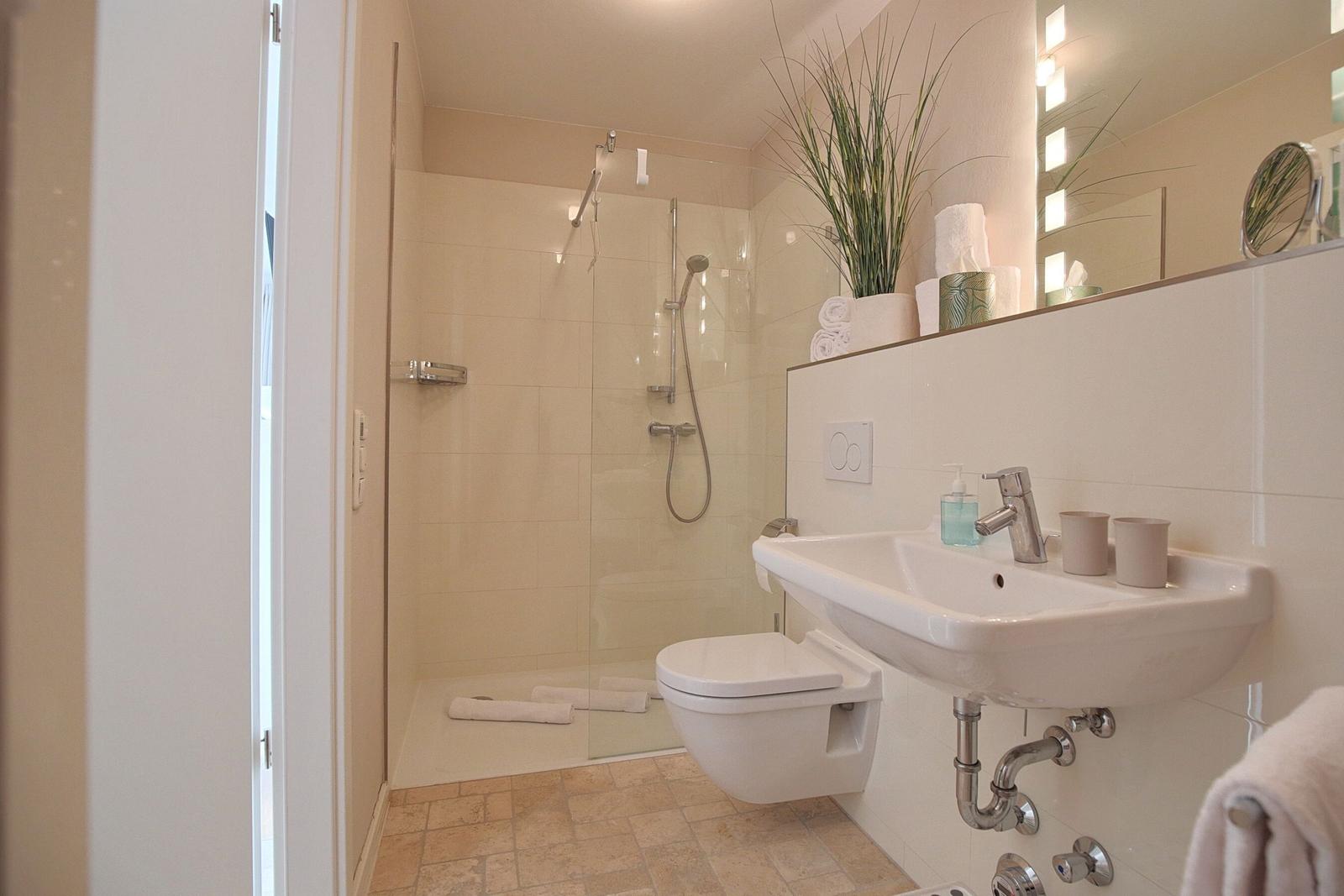 Badezimmer mit Dusche, Waschbecken und Toilette.