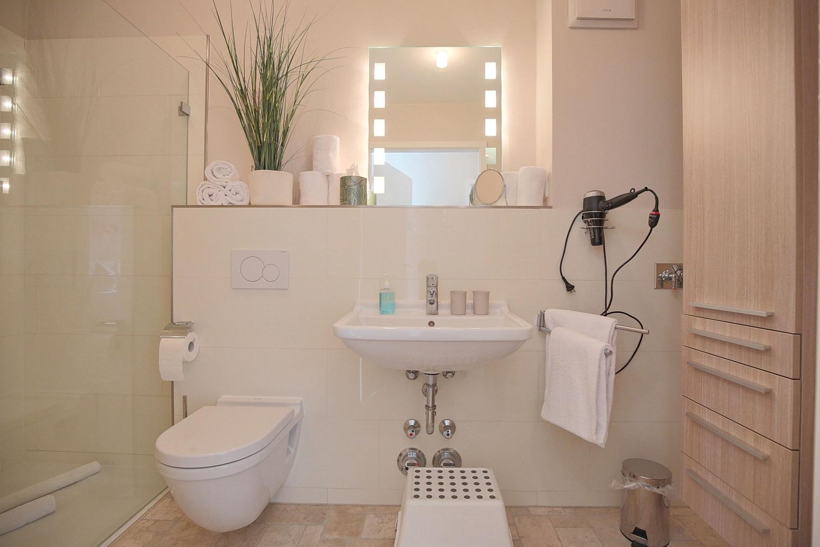 Badezimmer mit Dusche, Waschbecken, Toilette und Spiegelschrank.