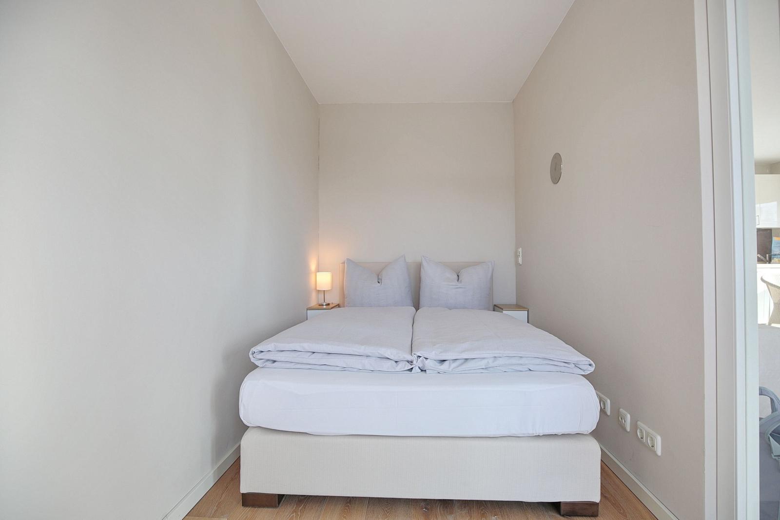 Schlafzimmer mit Doppelbett, Nachttisch und Lampe.