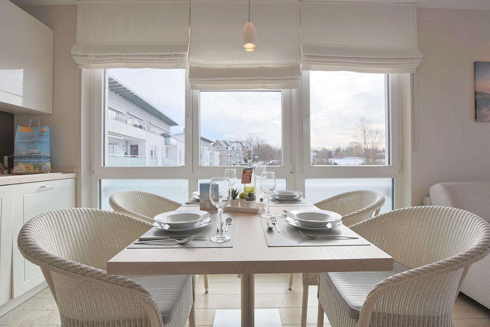 Esszimmer mit Tisch und Stühlen, großes Fenster mit Blick auf Außenbereich.
