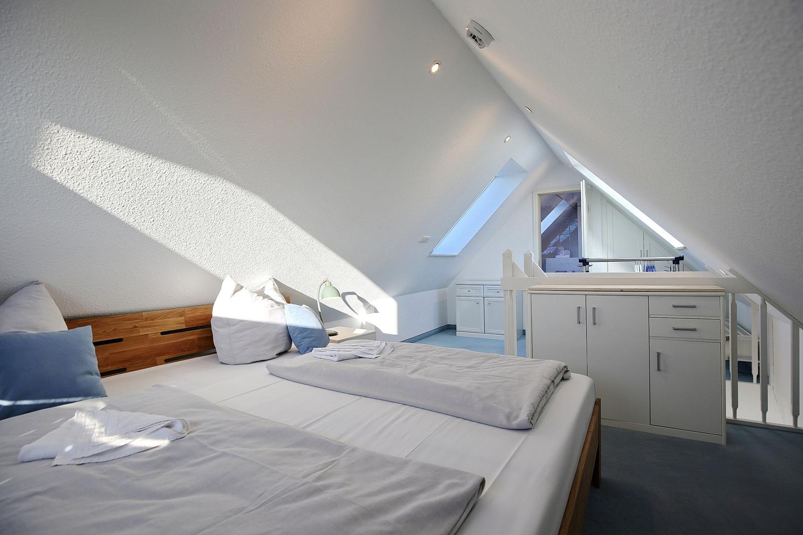 Schlafzimmer mit Dachschräge, Bett, Nachttisch und Schrank.