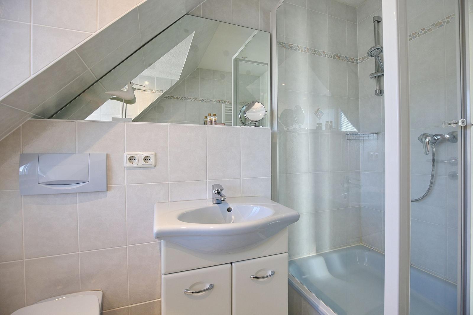 Badezimmer mit Dusche, Waschbecken und Spiegel unter Dachschräge