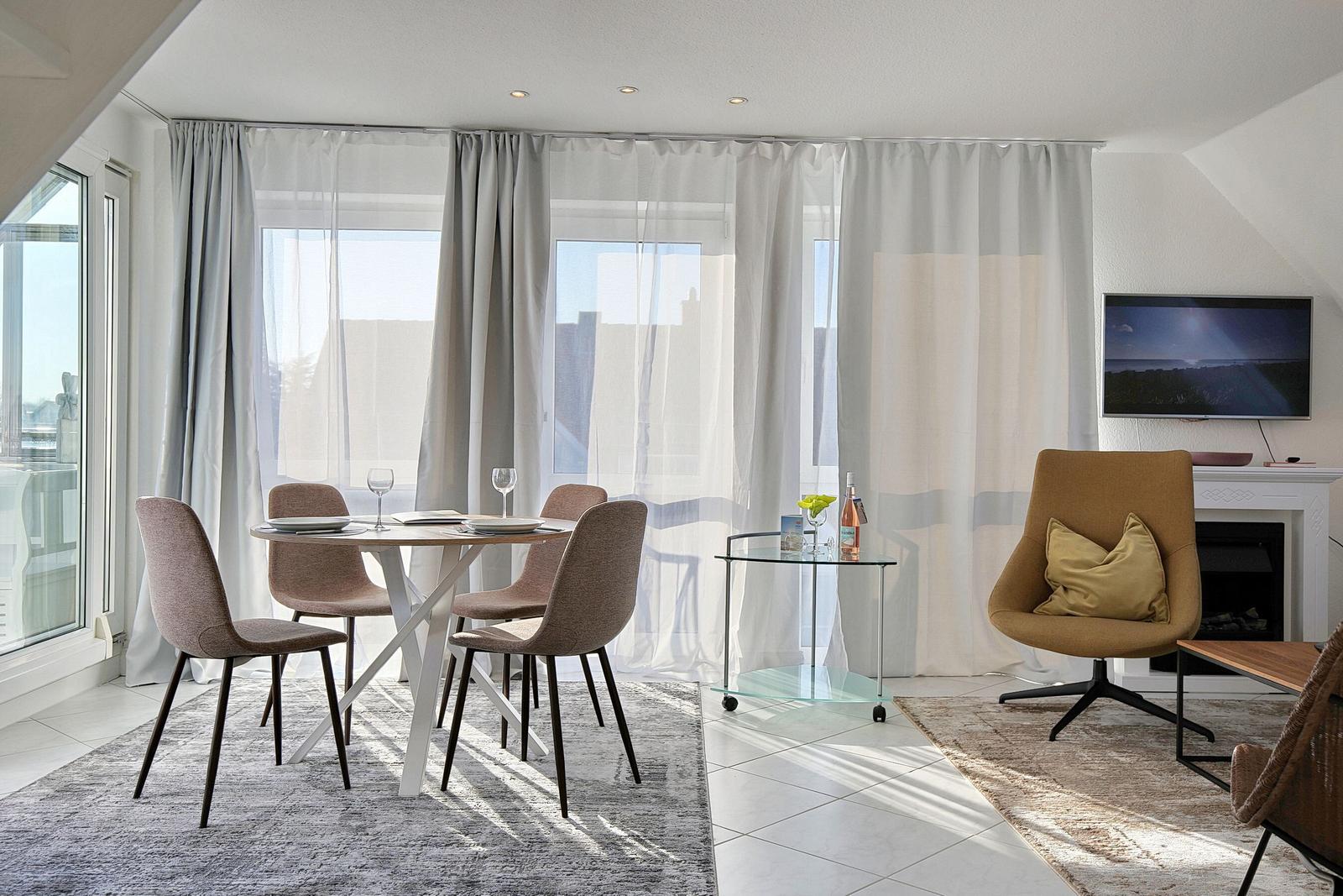 Essbereich mit Tisch und Stühlen, Sitzgelegenheit und Fernseher an der Wand.