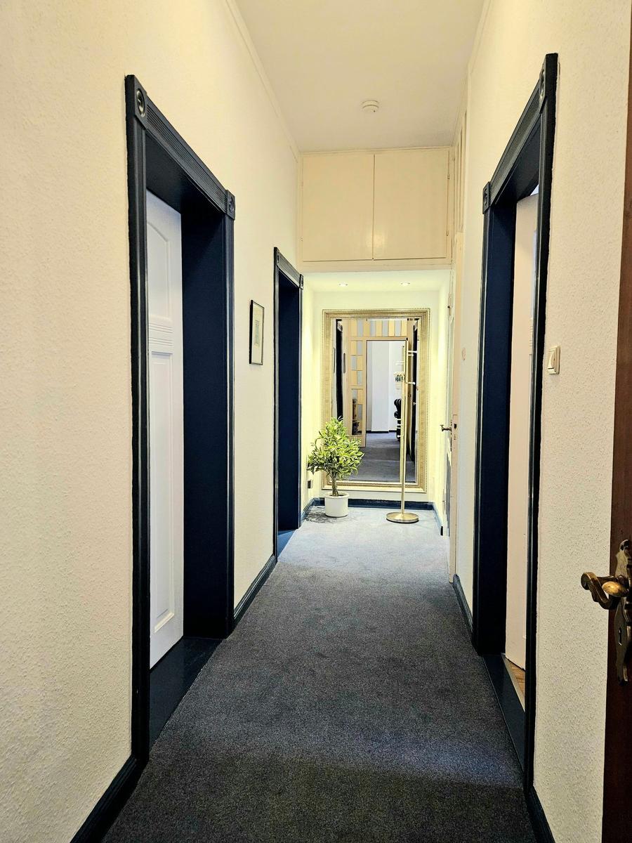 Flur mit Teppichboden, Türen und Pflanze. Spiegel und Schrank sind sichtbar.
