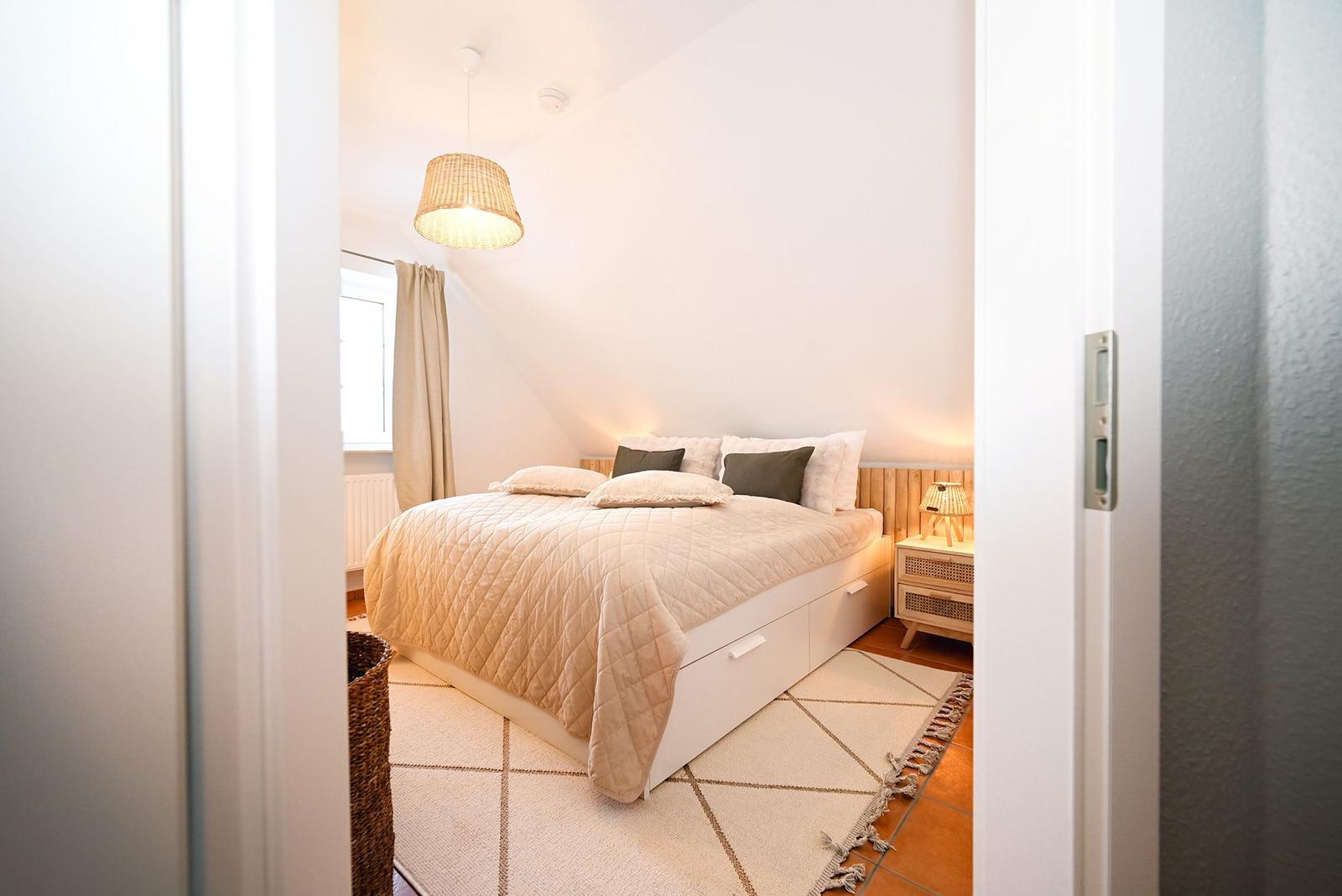 Schlafzimmer mit Bett, Nachttisch und Decke.