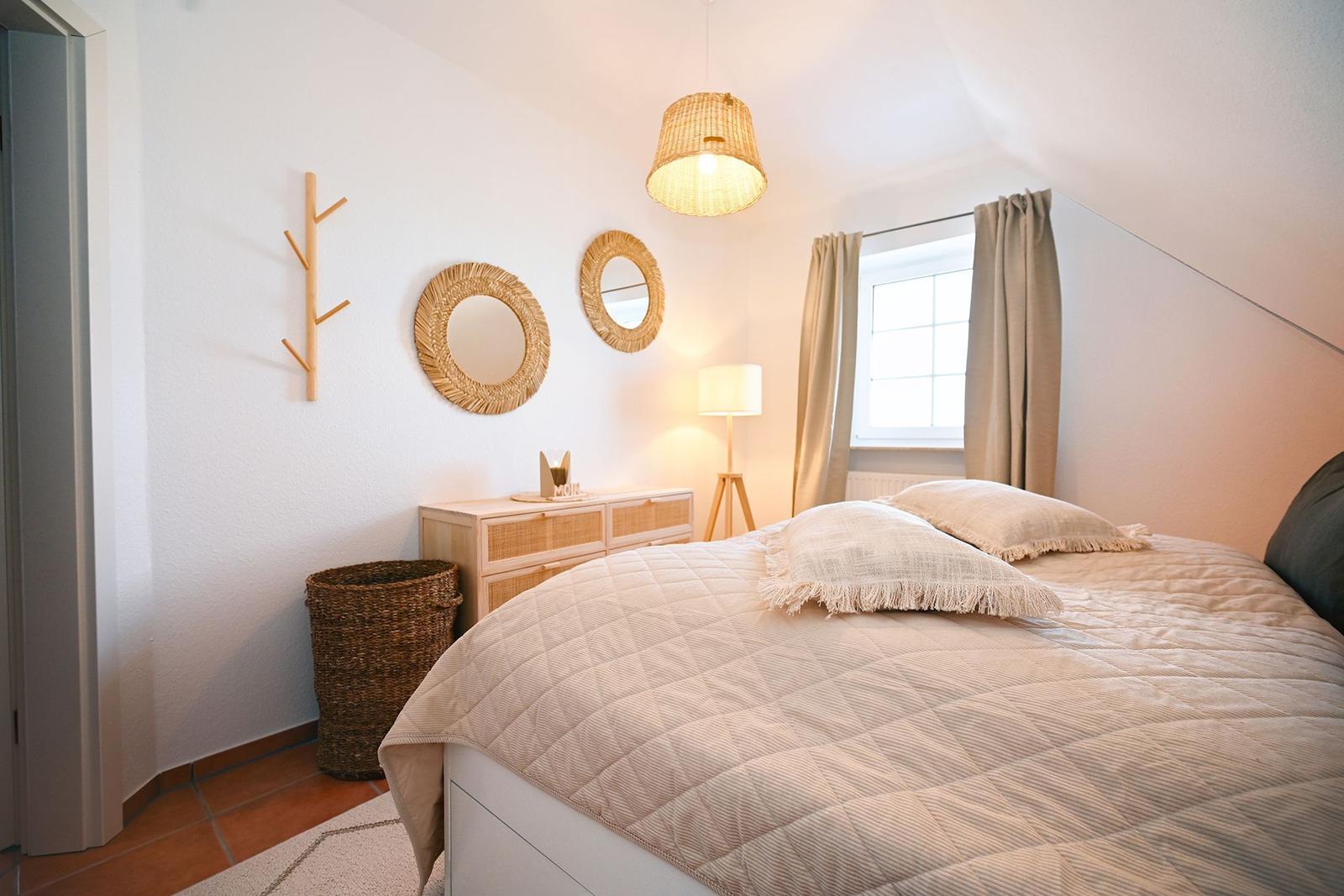 Schlafzimmer mit Bett, Nachttisch, Lampe und Fenster