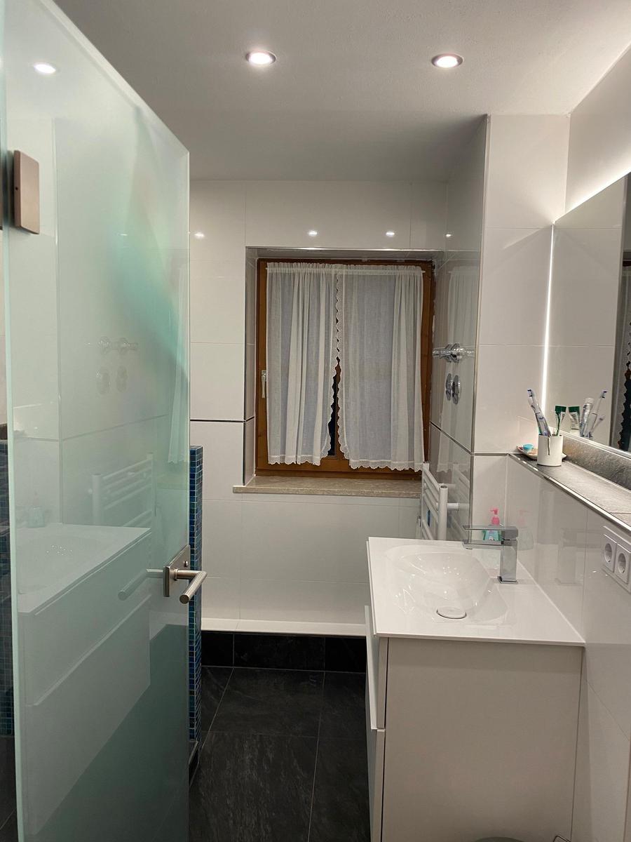 Bathroom with shower, sink, and window.