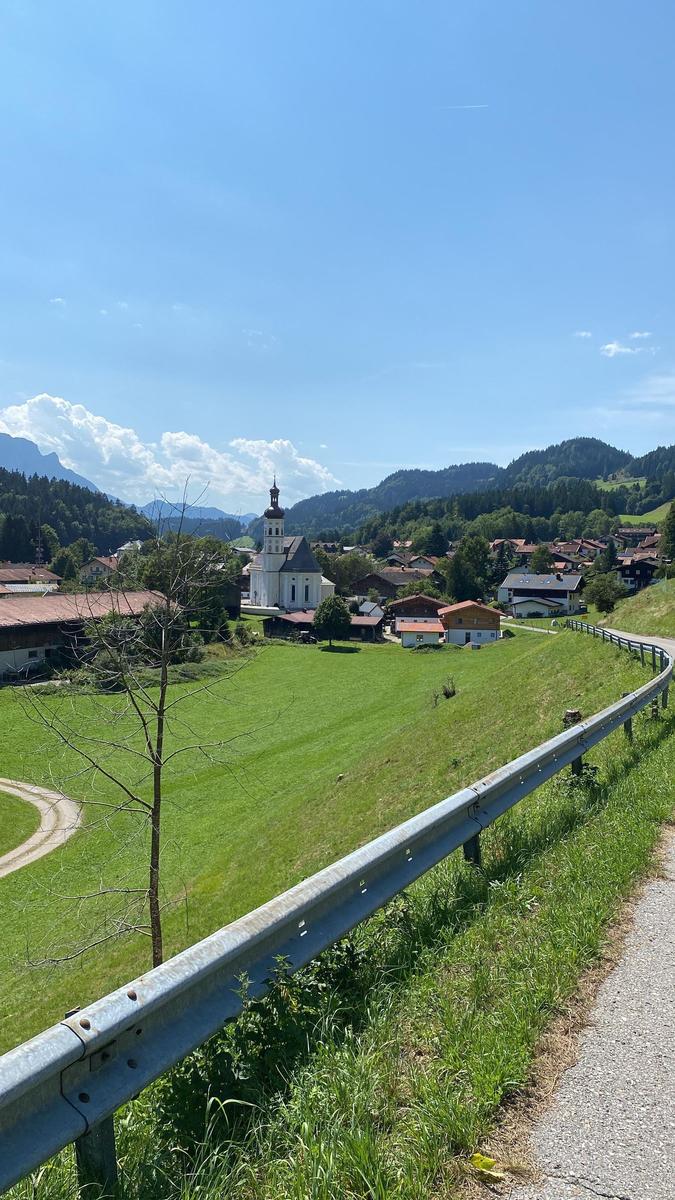 Wide view of a scenic mountain landscape with church and villages.