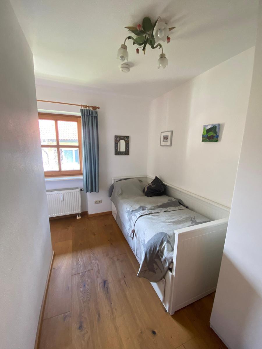 Bedroom with bed, window, and wooden floor.