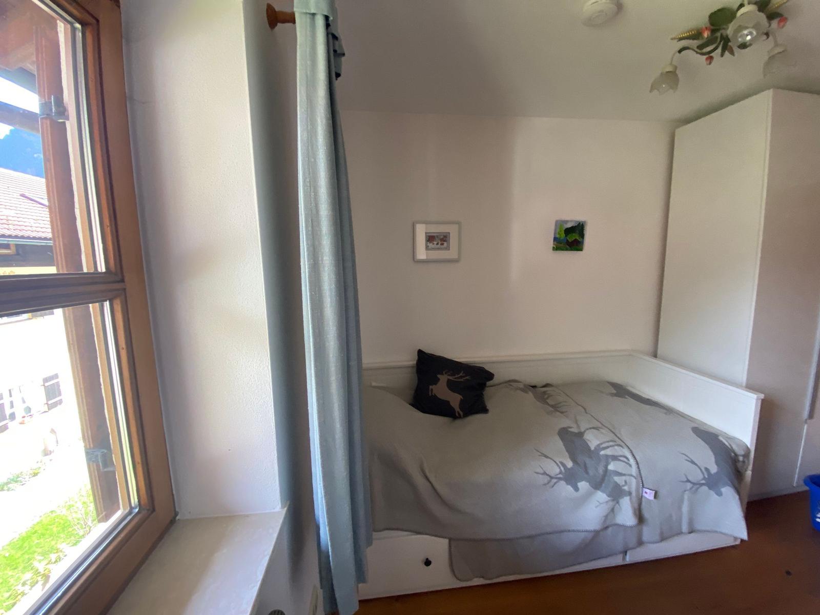 Bedroom with bed, window, and wardrobe.