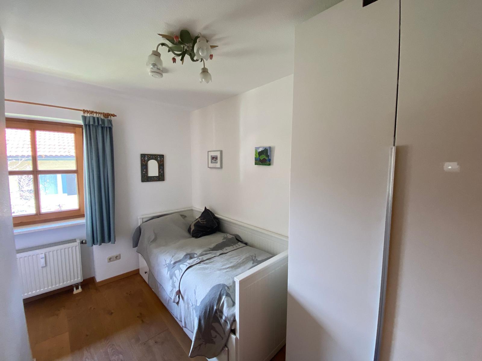 A bedroom with bed, window, curtain, and wardrobe.