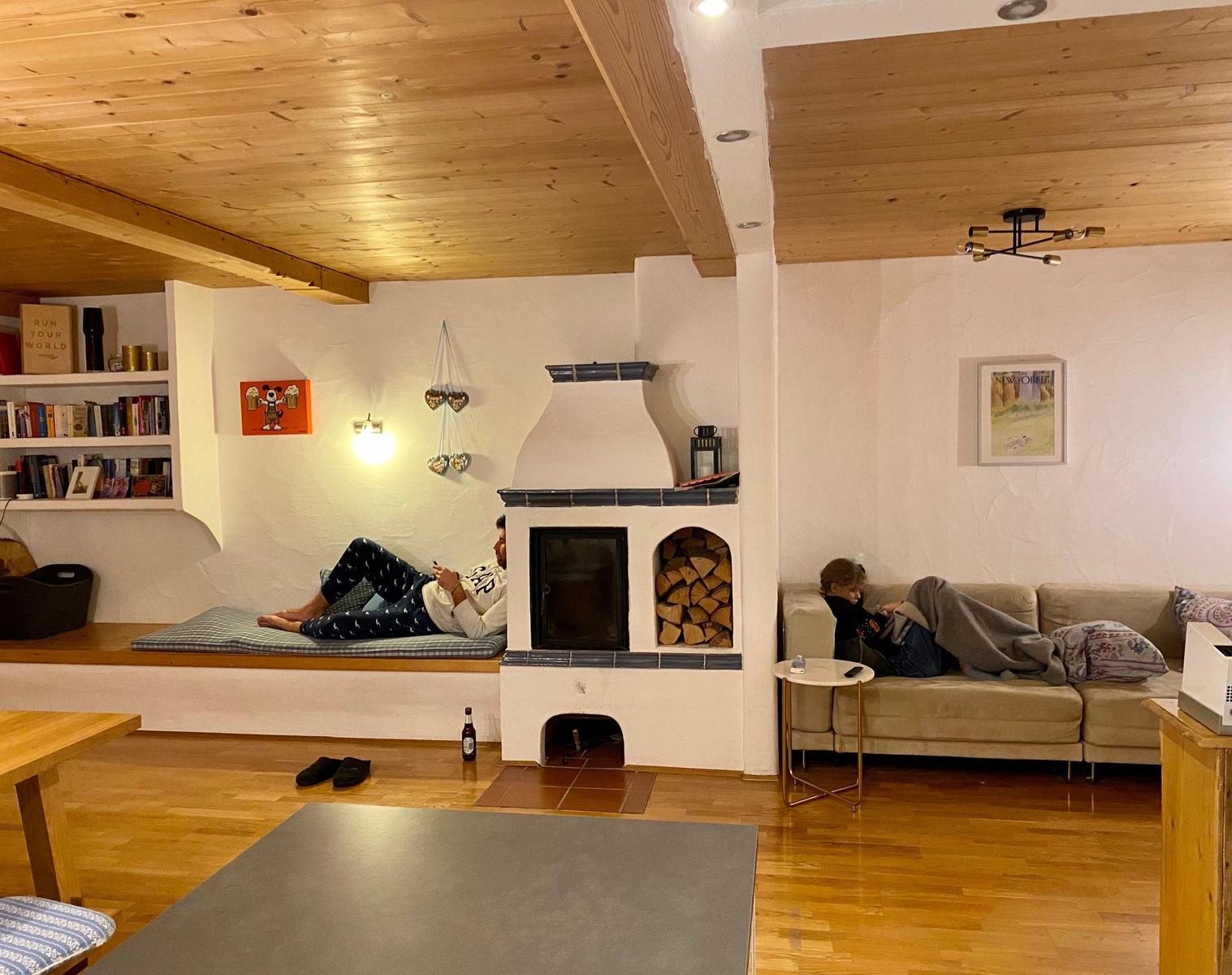 Living room with fireplace, sofa, and seating area. Wooden ceiling and hardwood floor.
