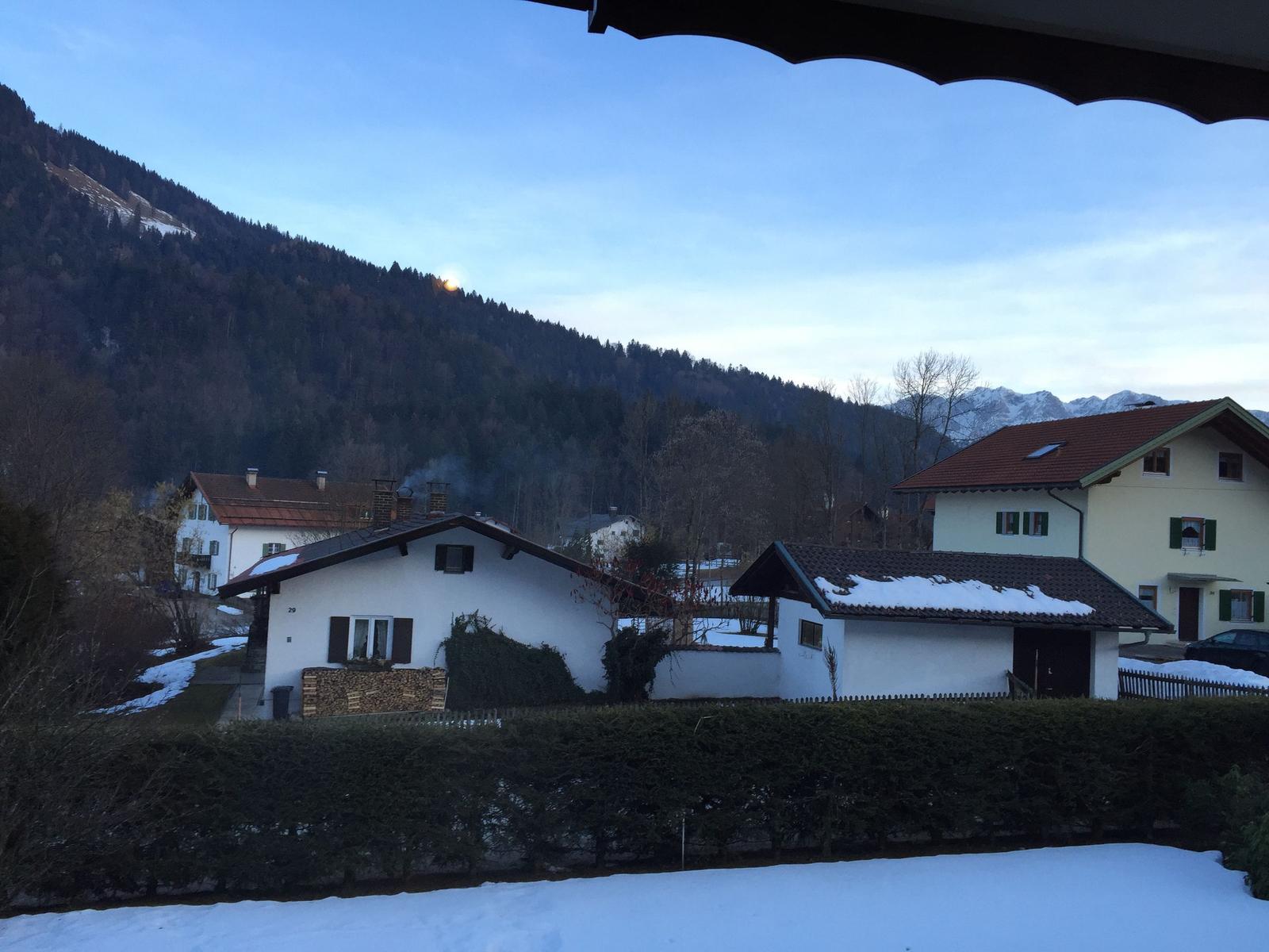 Snow-covered view of houses and mountains at dusk.