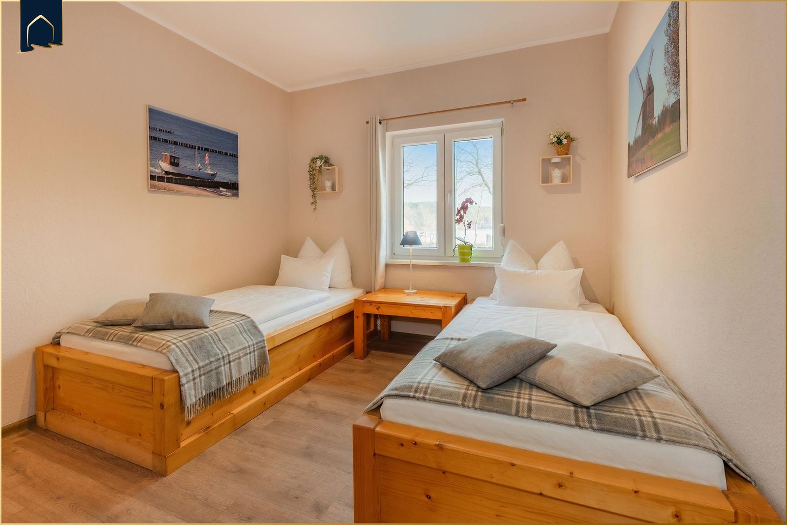 Zwei Schlafzimmer mit Holzbetten und Fenster.