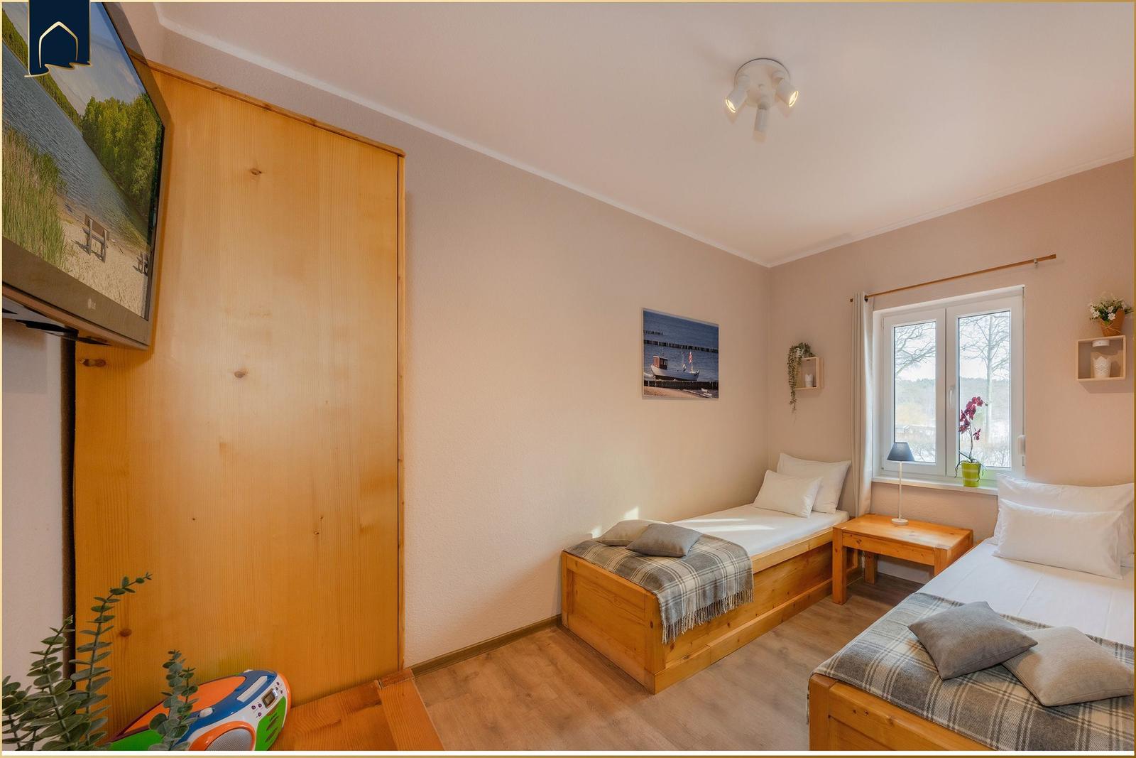 Zwei Schlafzimmer mit Holzbetten, Fenster und Wandbildern.