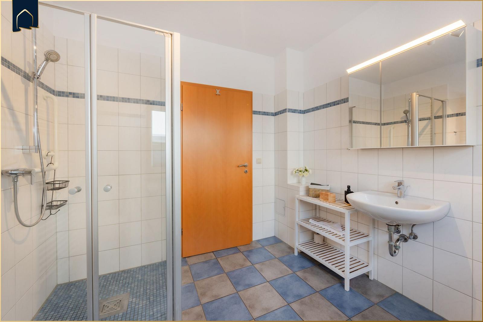 Badezimmer mit Dusche, Waschbecken und Spiegel