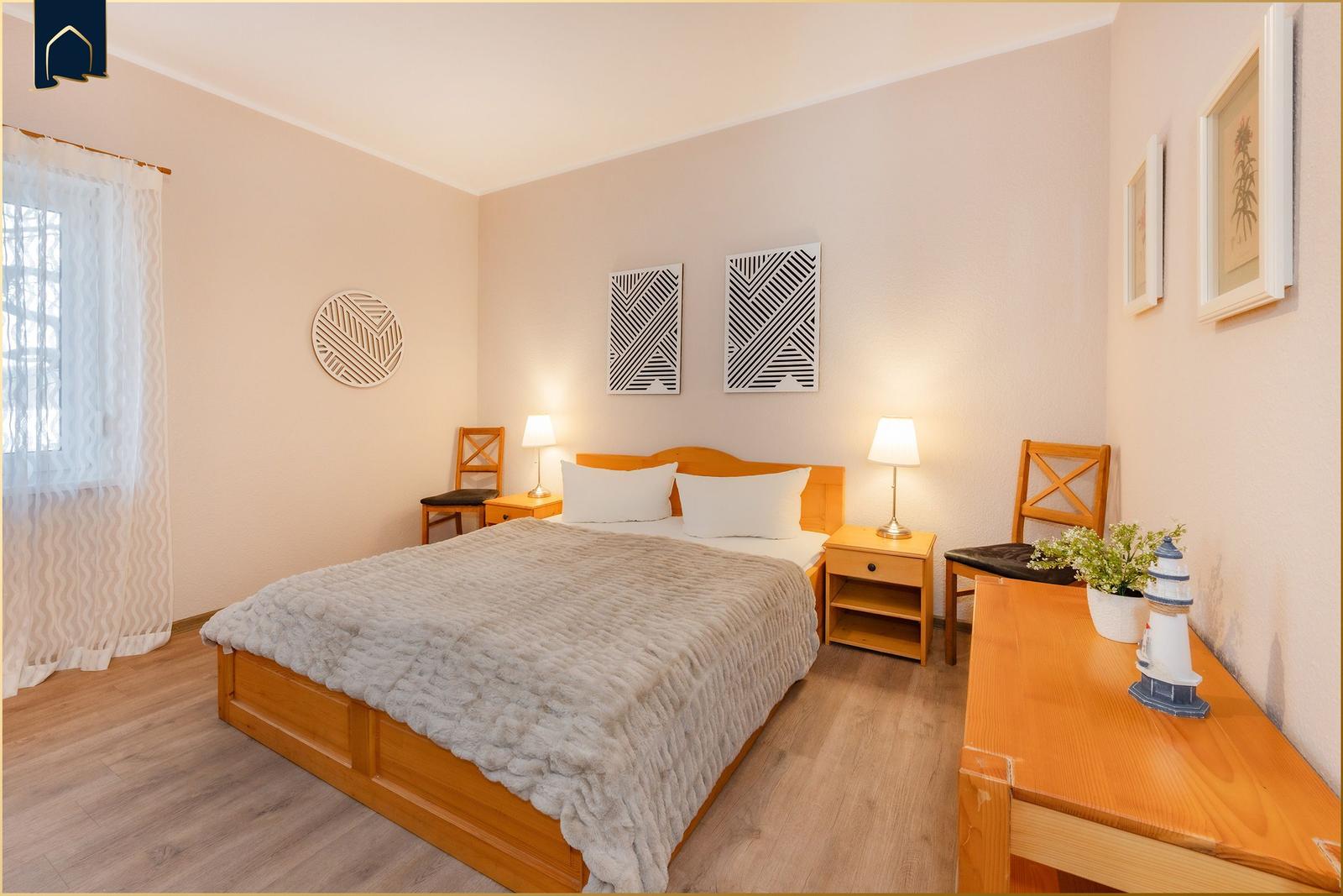 Schlafzimmer mit Bett, Nachttischen und Schreibtisch.