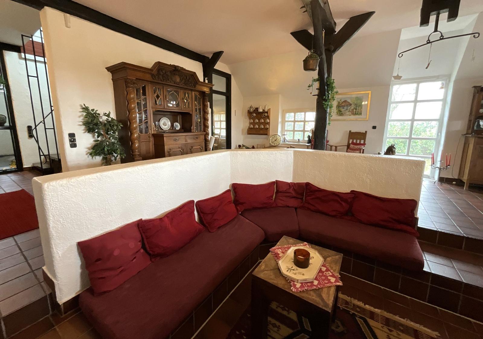 Wohnbereich mit L-förmigem Sofa und Holzmöbeln.