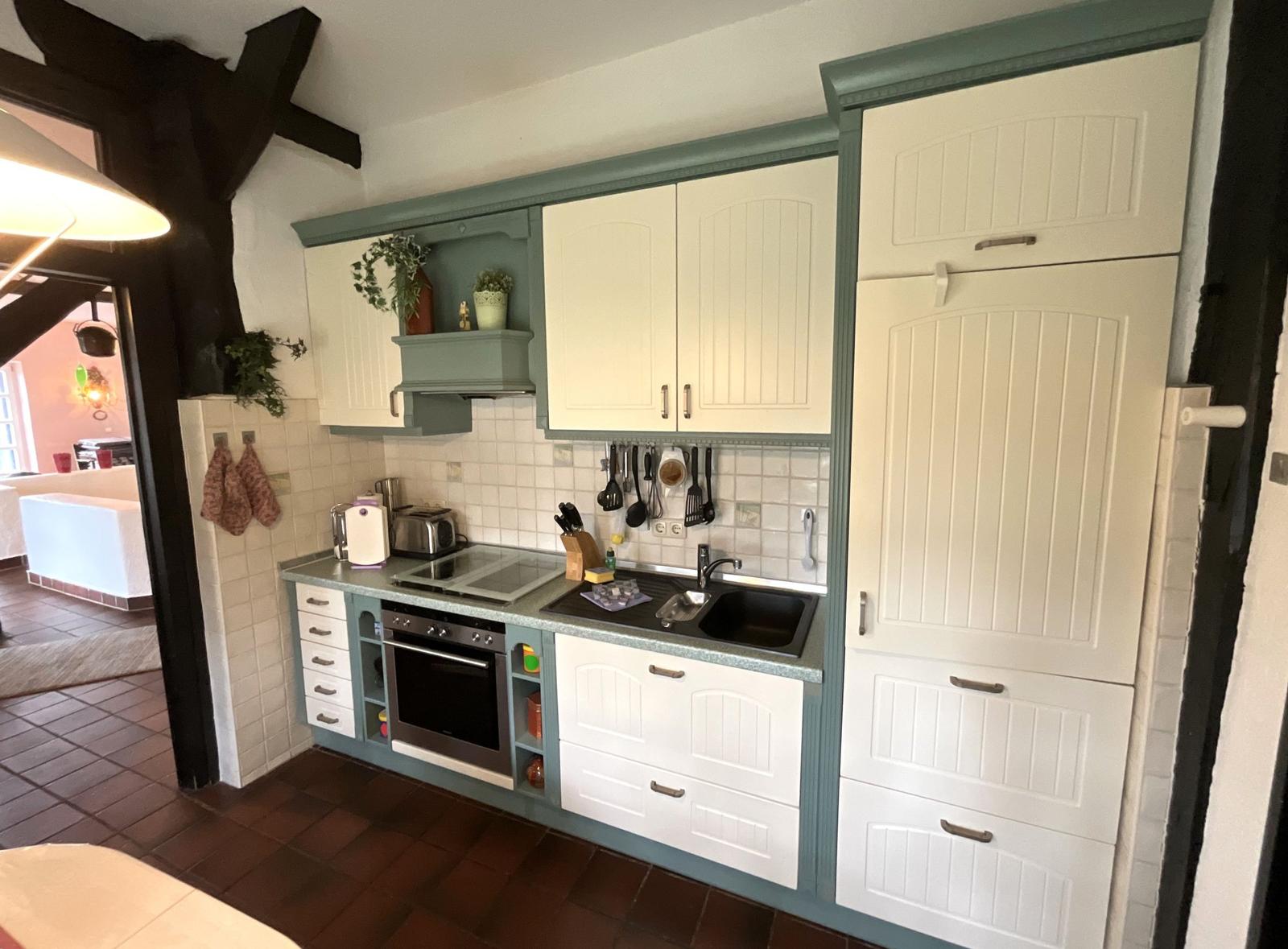 Küche mit weißen Schränken, grünem Rahmen und Backofen.