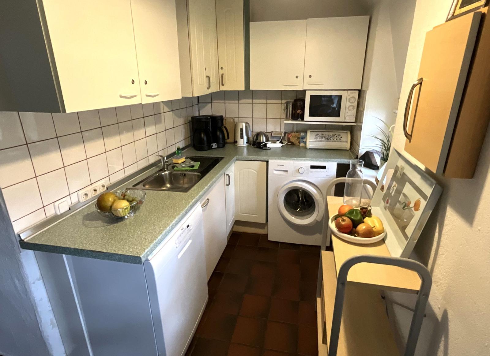 Küche mit Spüle, Waschmaschine und Mikrowelle.