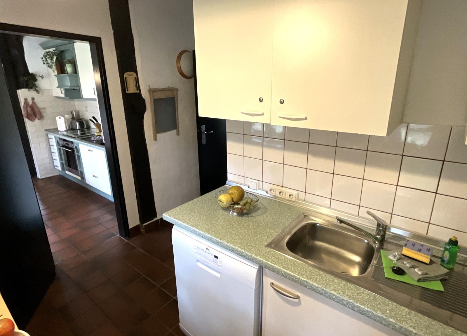 Küche mit Spüle, Waschmaschine und Obstschale auf Arbeitsfläche