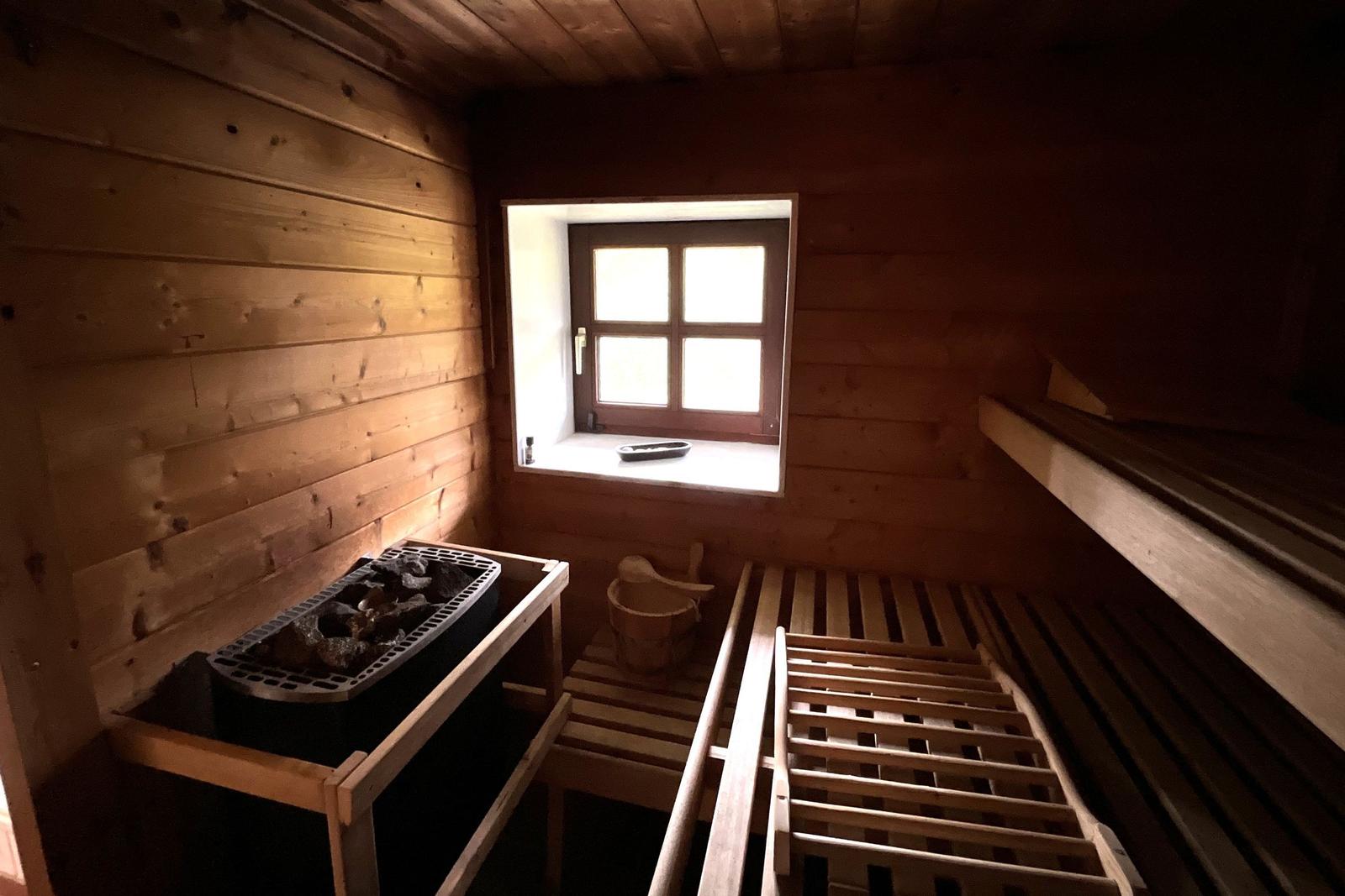 Sauna mit Holzwand, Sitzbänken und Fenster