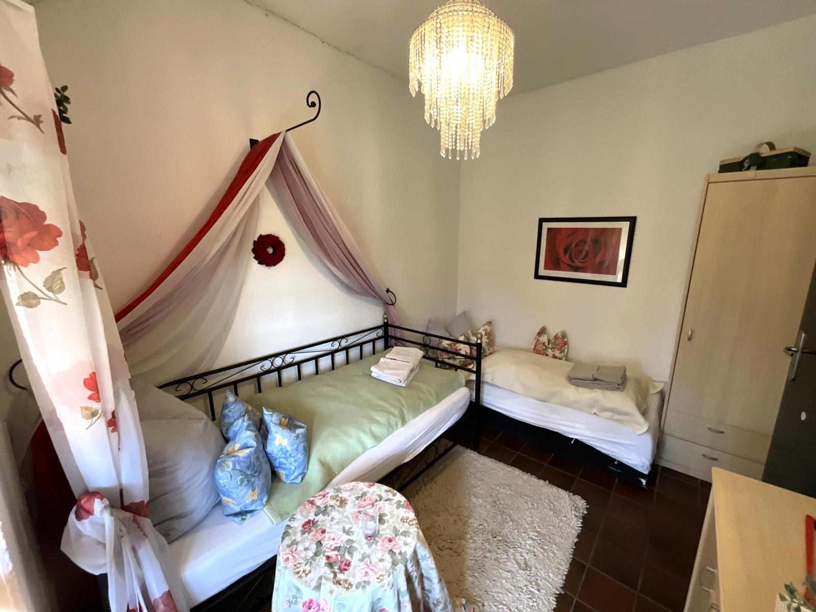 Schlafzimmer mit zwei Betten, Kronleuchter und Kleiderschrank