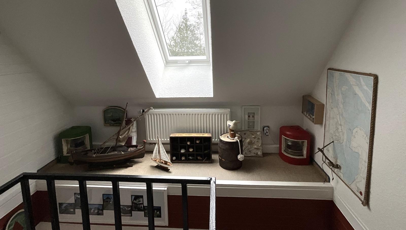 Dachboden mit Modellbooten, Karte und Heizkörper unter Dachfenster.