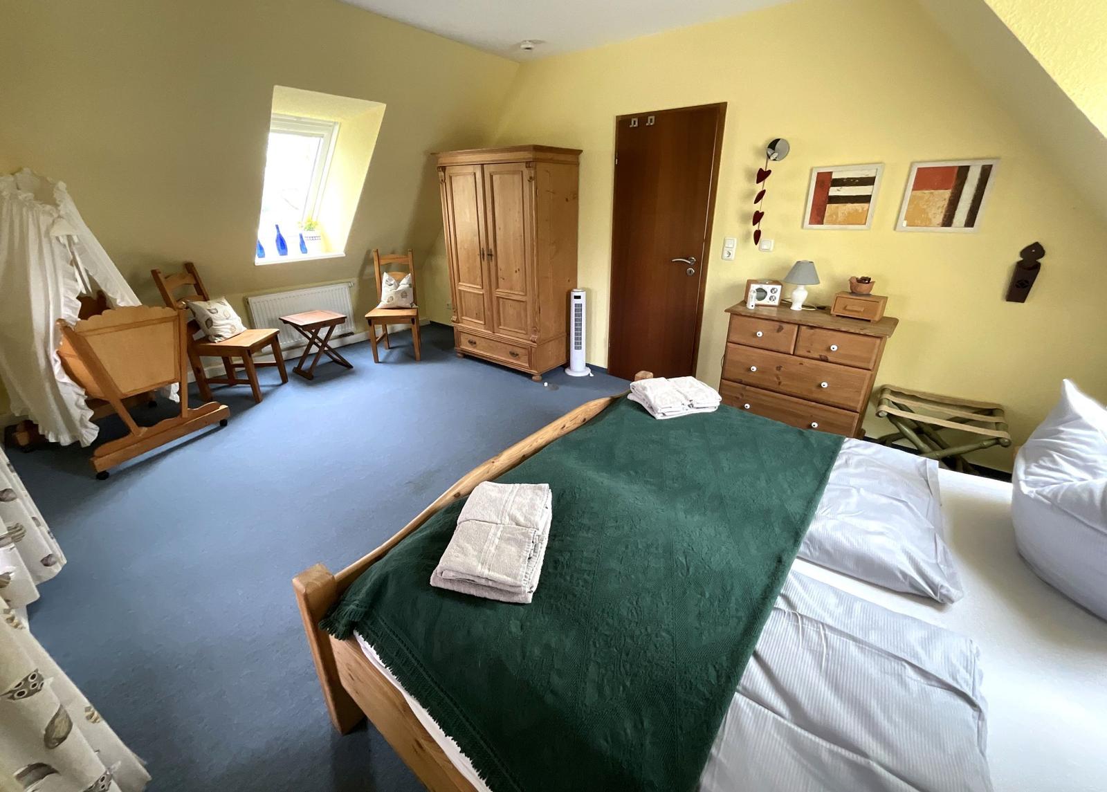 Schlafzimmer mit Bett, Kleiderschrank und Fenster