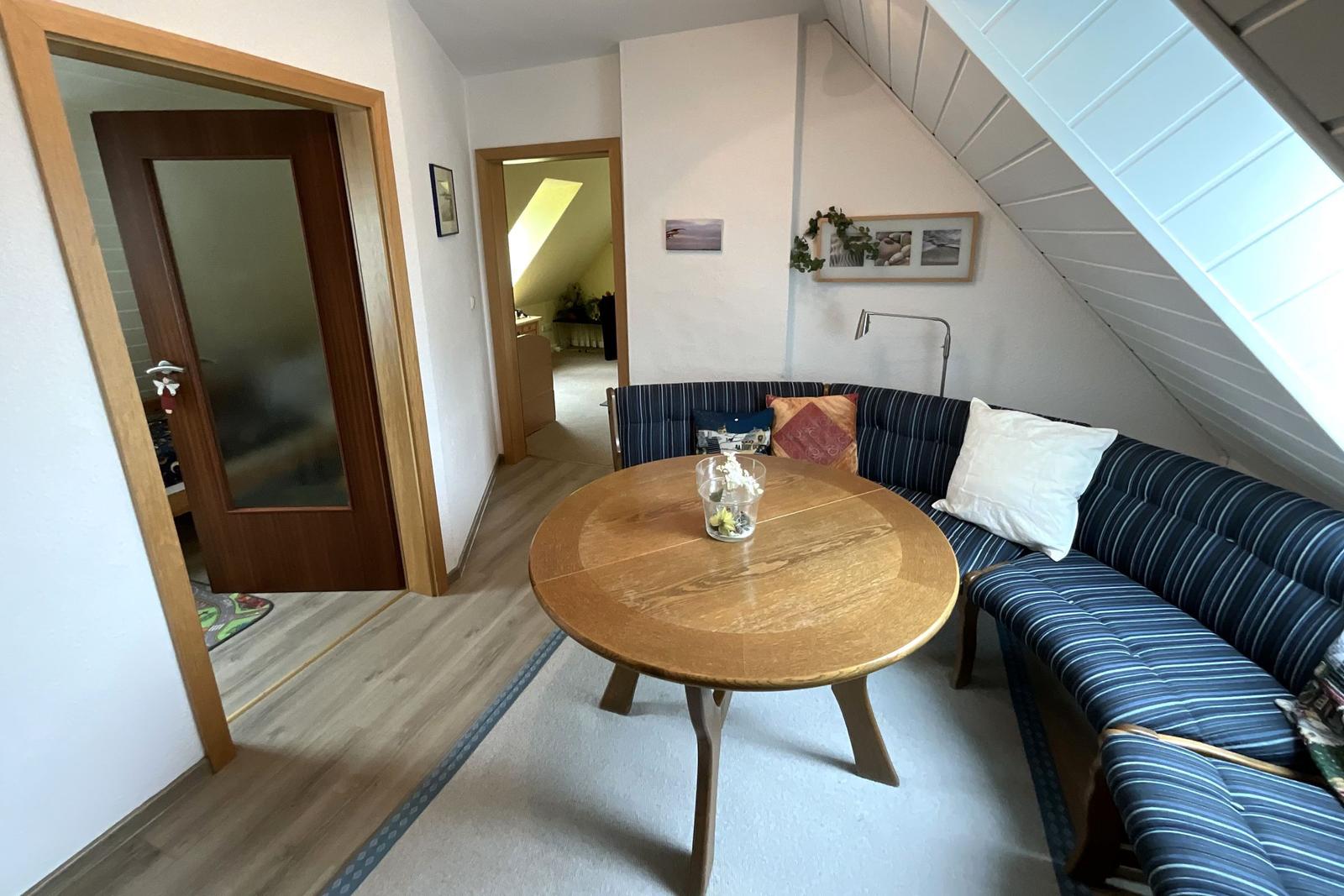 Wohnzimmer mit Schlafcouch, runden Tisch und schrägen Dachbodenwänden.