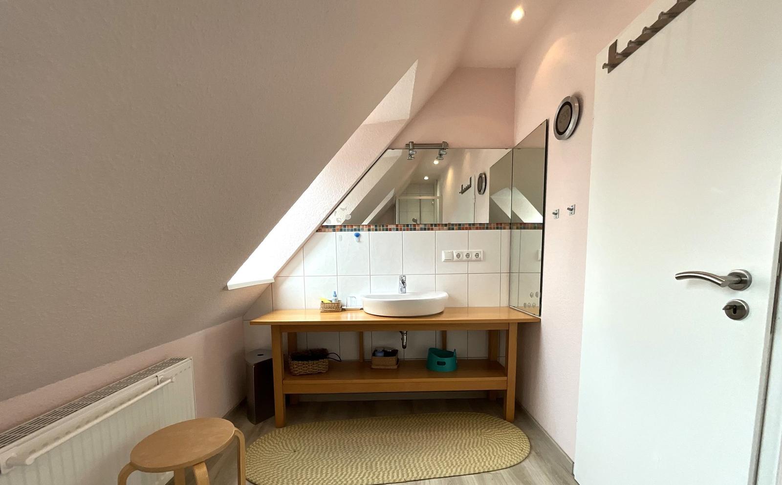Badezimmer mit Waschtisch, Spiegel und Dachschrägen