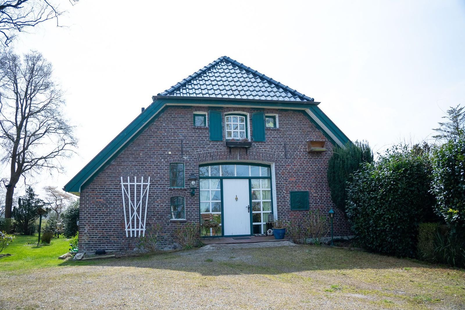 Ein Backsteinhaus mit grünen Fensterläden und einer weißen Haustür.