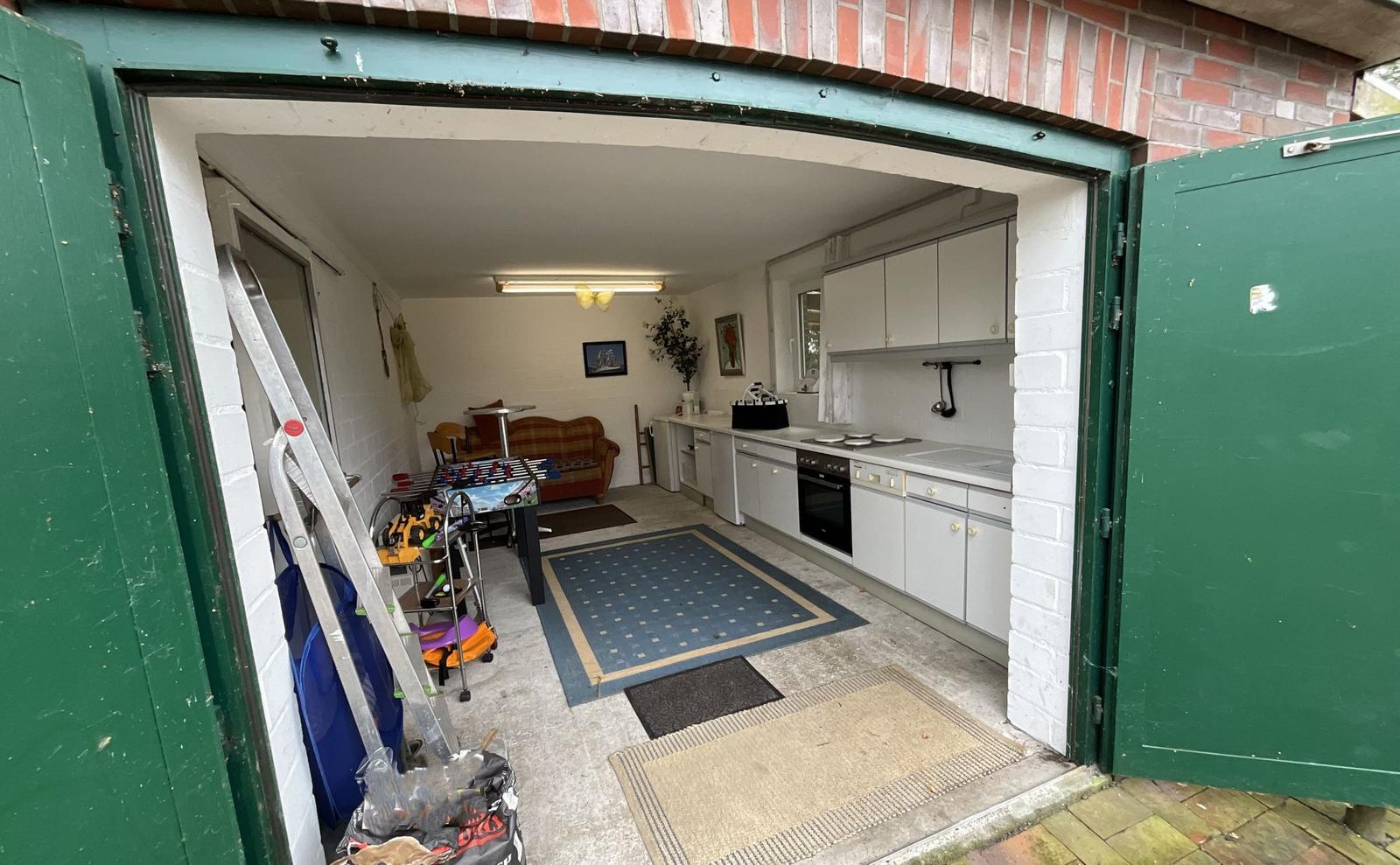 Küche mit weißen Schränken und Wohnbereich mit Sofa und Tisch.