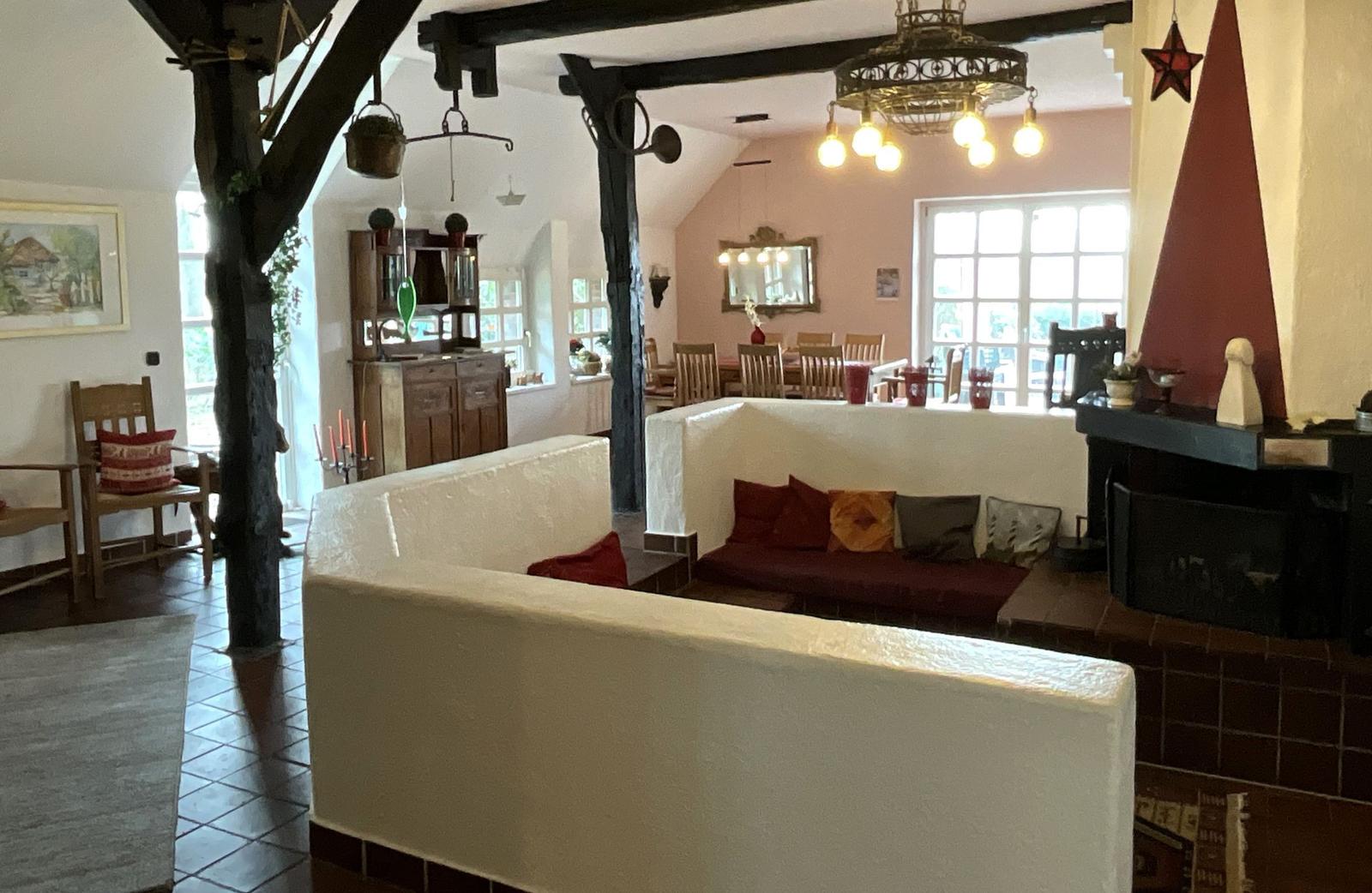 Wohn- und Essbereich mit Kamin, Holzbalken und rustikaler Einrichtung.