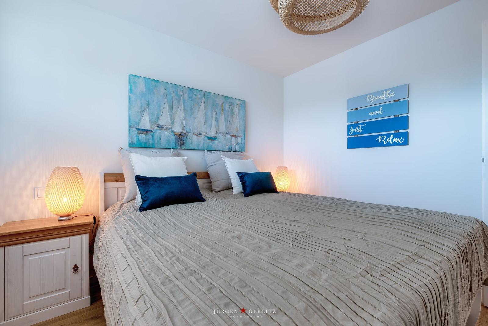 Schlafzimmer mit Bett, Nachttisch und Wanddekoration.