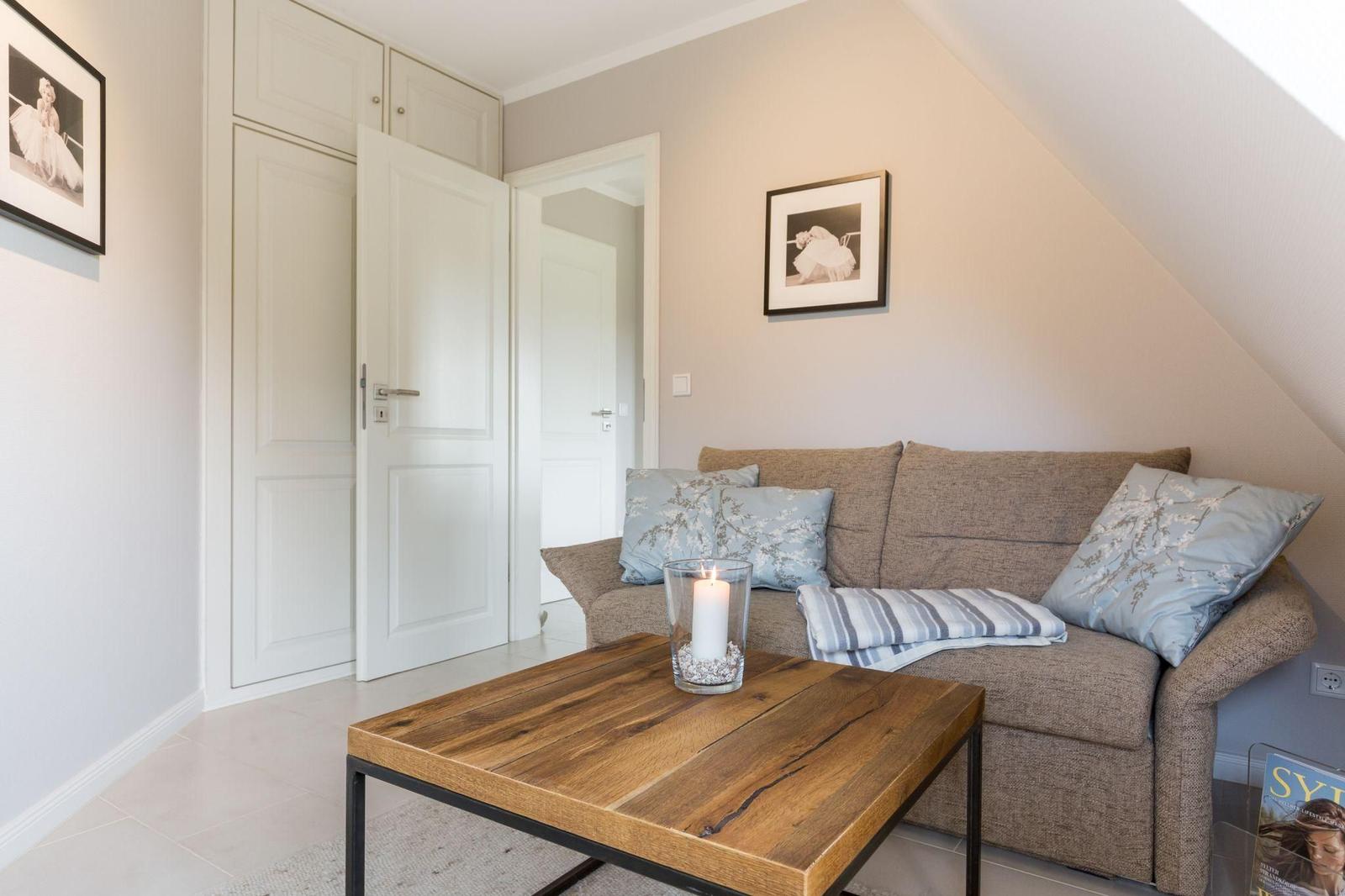 Wohnzimmer mit Sofa, Tisch und Bildern an der Wand.