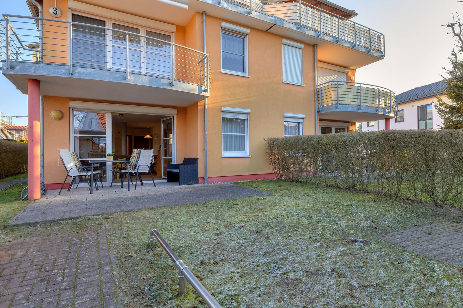 Orangerotes Haus mit Balkon, Terrasse und Garten. Durchgangstür zum Innenraum.