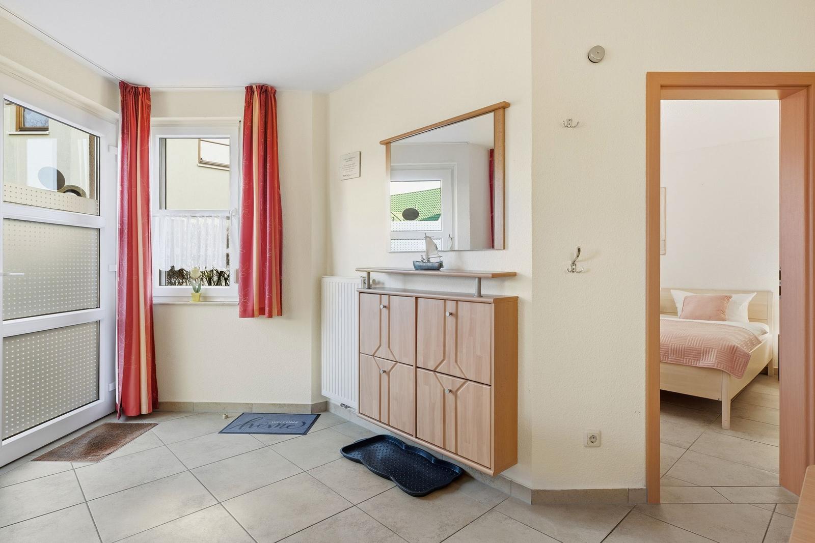 Eingangsbereich mit Garderobe, Spiegel und Blick in Schlafzimmer.