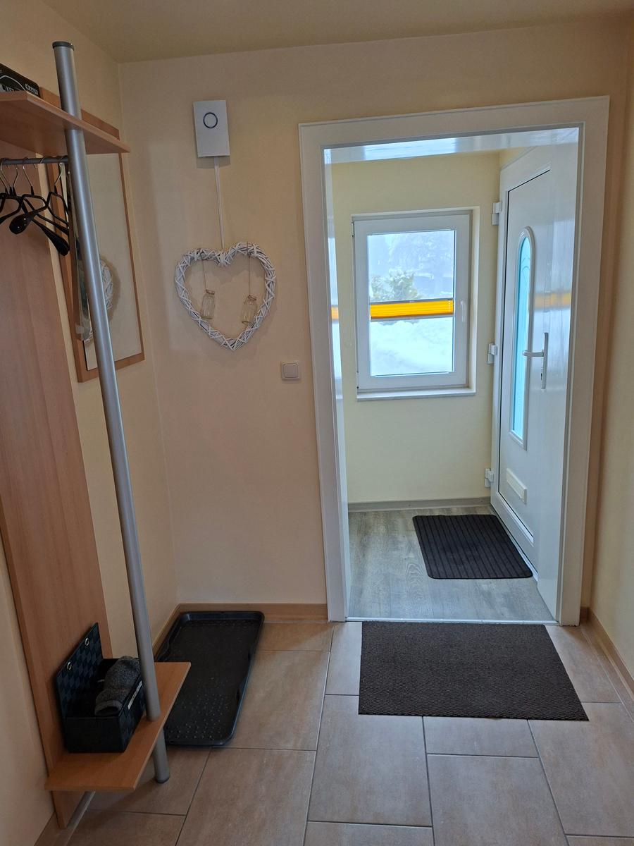 Eingangsbereich mit Garderobe, Herzdekoration und Blick auf die Haustür.