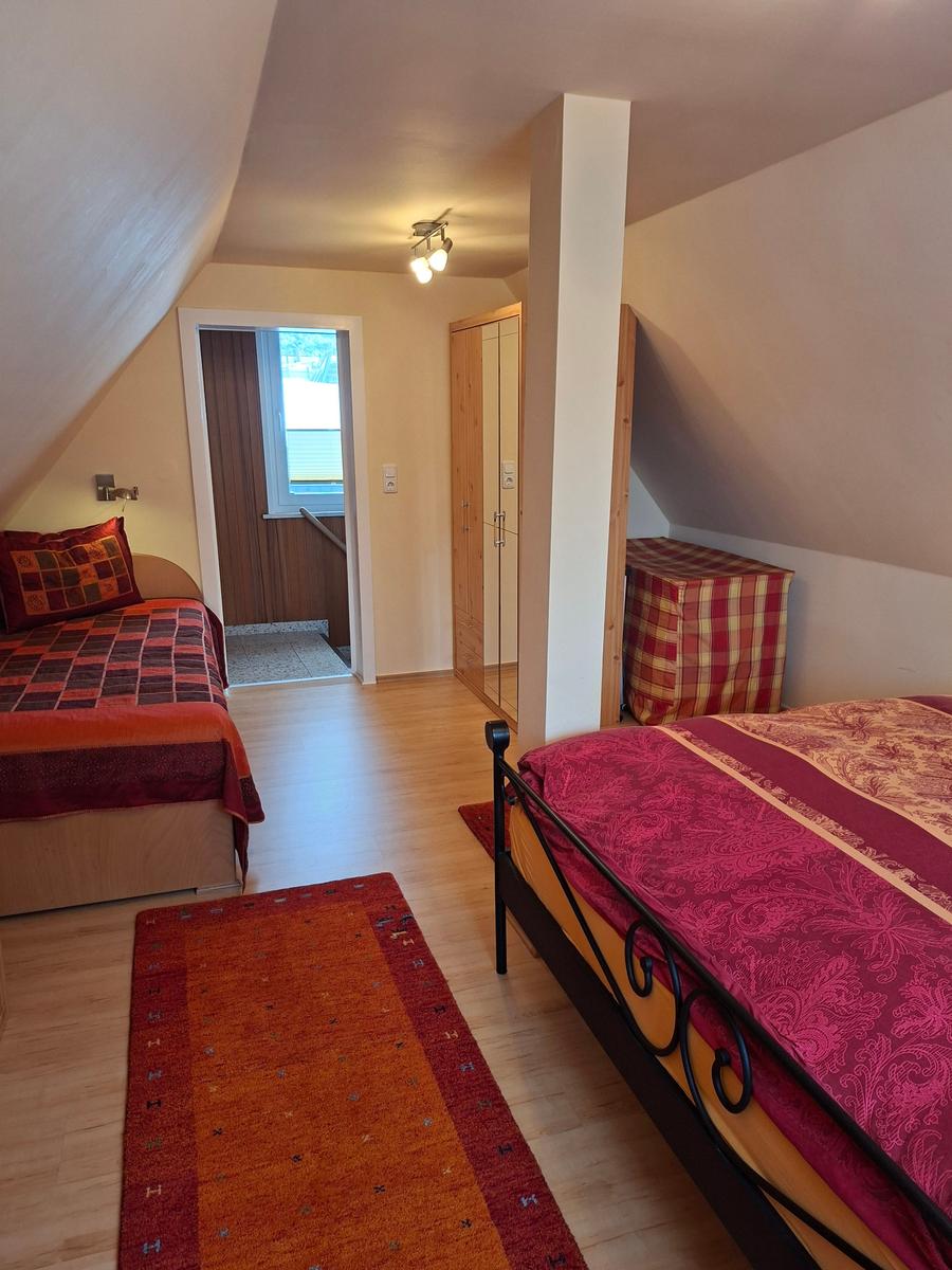 Zwei Schlafzimmer mit Betten, Holzboden und Dachschrägen.