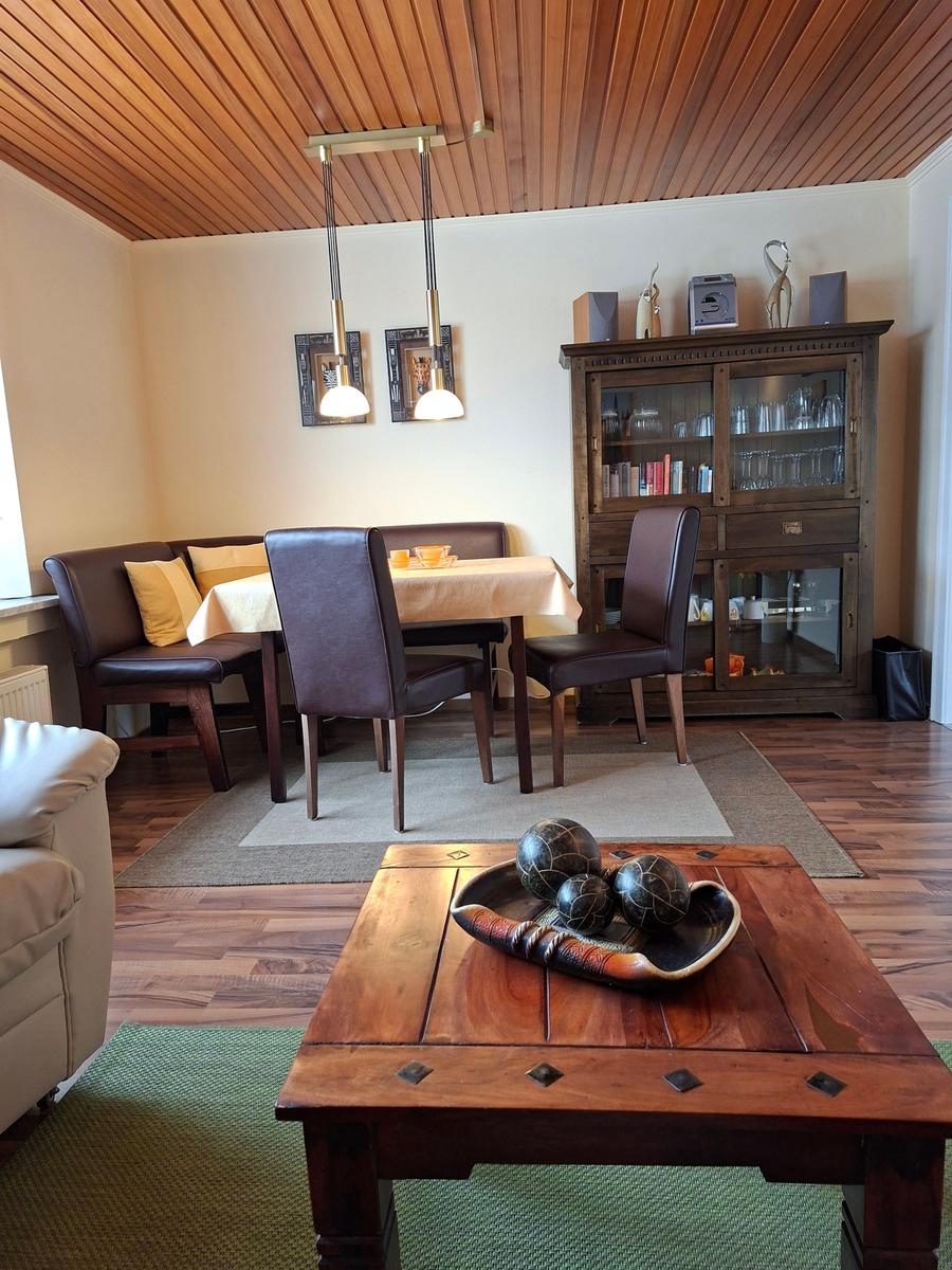 Essbereich mit Holztisch, Stühlen und Sideboard. Holzdecke und Parkettboden.