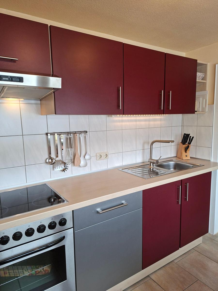 Küche mit roten Schränken, Edelstahlspüle und Herd
