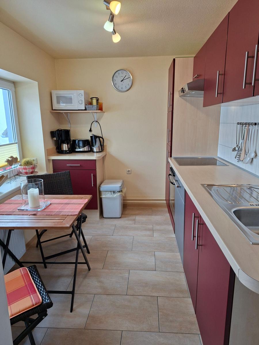 Küche mit roten Schränken, Esstisch und Küchenzeile