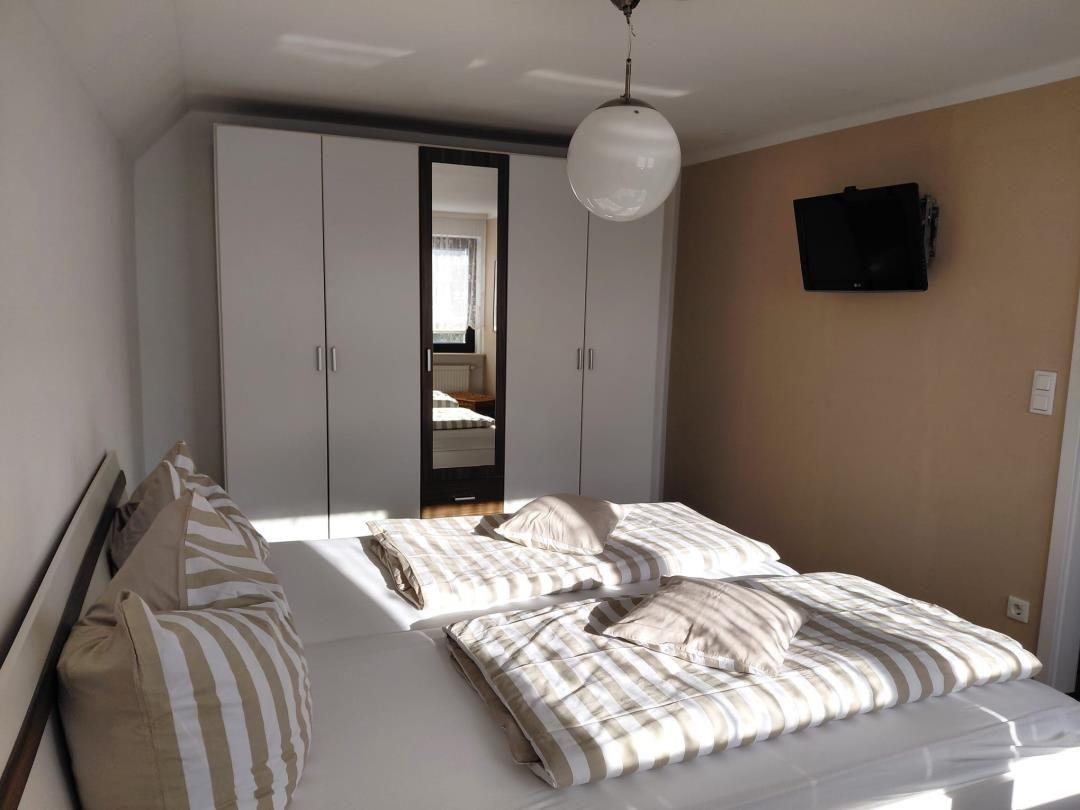 Schlafzimmer mit Bett, Kleiderschrank und Wand-TV.