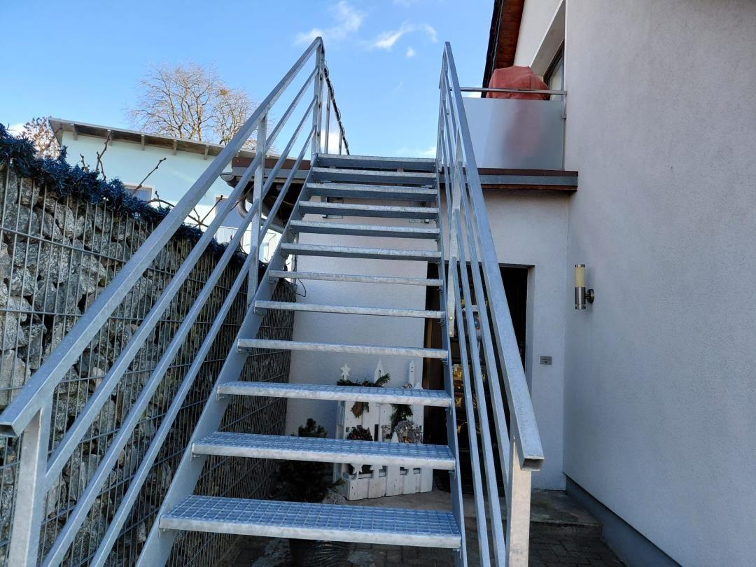 Metalltreppe führt zu einer Terrasse an der Hauswand.