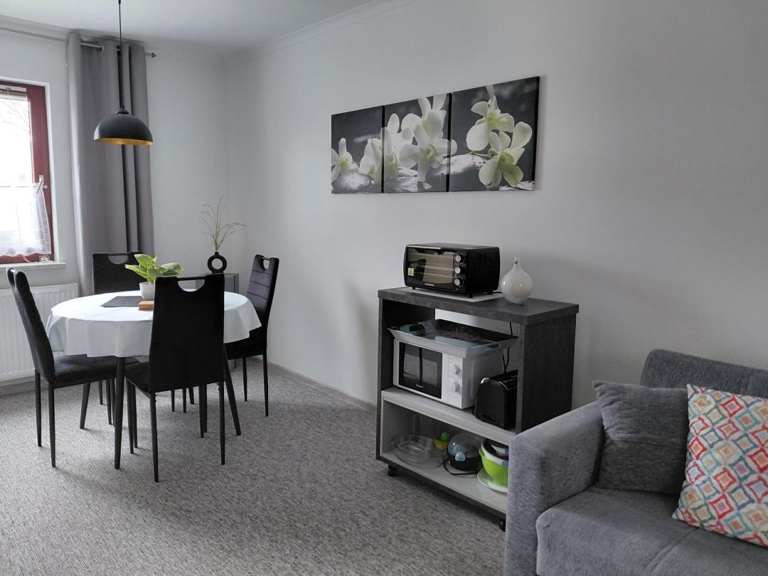 Wohn- und Essbereich mit Sofa, Esstisch und Küchenzeile.