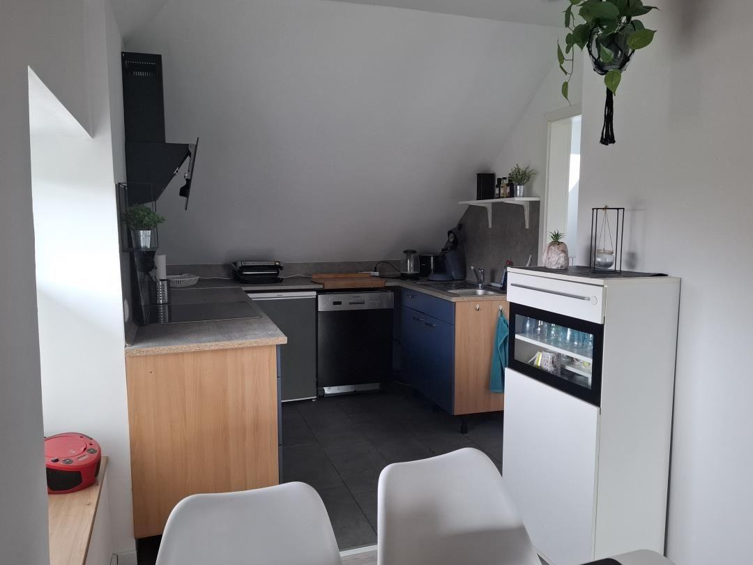 Küche mit Arbeitsplatten, Spüle, Kochfeld und Kühlschrank.