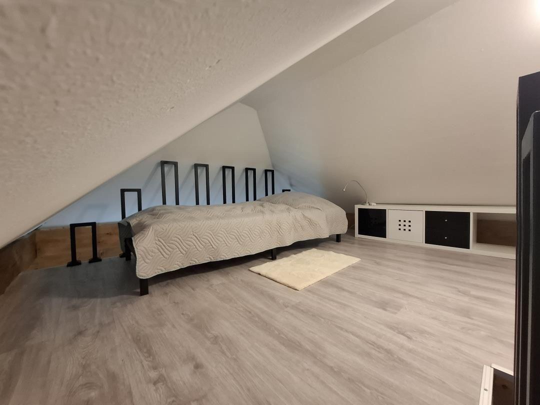 Schlafzimmer mit Dachschrägen, Bett, Kleiderschrank und Teppich.