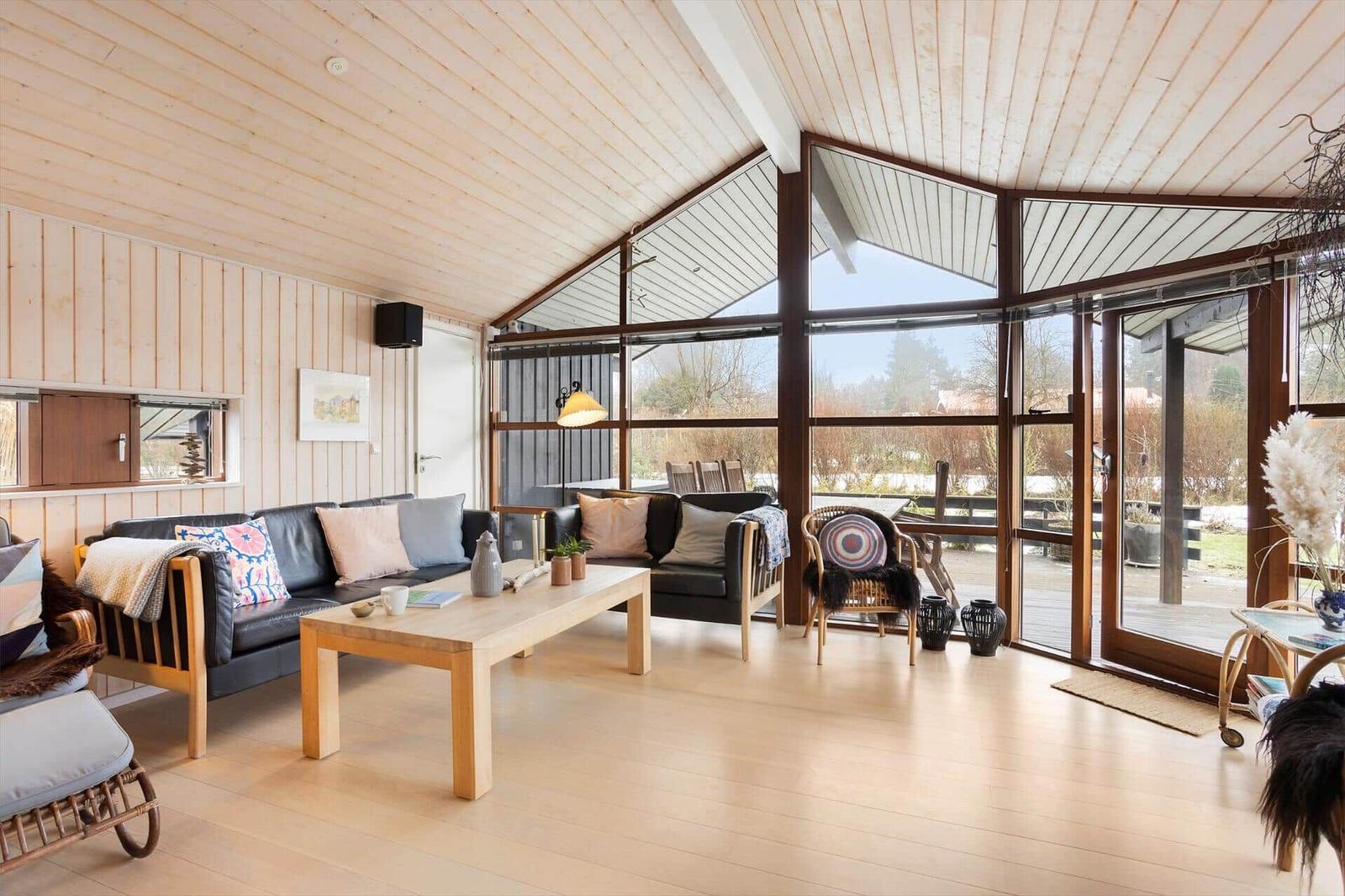 Living room with wooden ceiling, large window, and sofa with cushions.