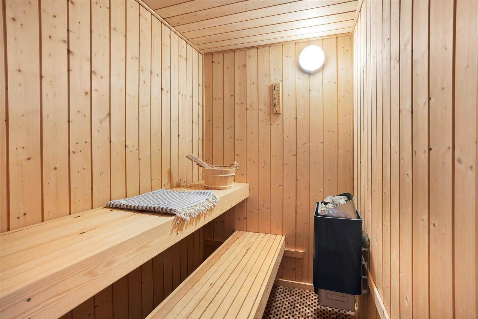Sauna with wooden walls, bench, and wooden tub with bucket.